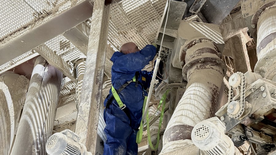 Techniker mit Klettergeschirr bei Wartung in Industrieanlage